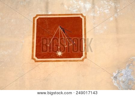 Sundial clock on old house wall in Barga, Italy