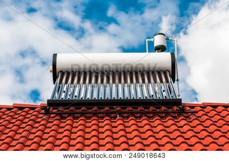 Solar Water Heater Boiler On Residentual House Rooftop, Blue Sky With White Sky Background.