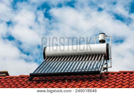 Solar Water Heater Boiler On Residentual House Rooftop, Blue Sky With White Sky Background.