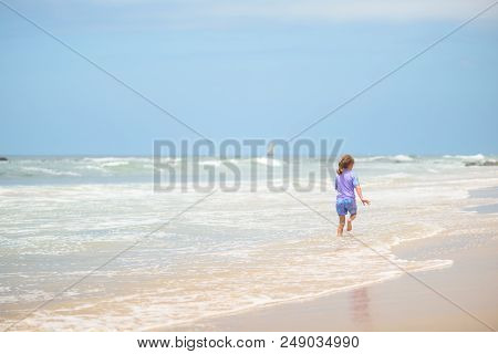 Happy Girl In Purple Swimsuit Running On The Beach In The Waves, Family On Vacation, View From Behin