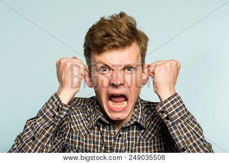 Emotional Breakdown. Angry Enraged Infuriated Crazy Man Screaming. Portrait Of A Young Guy On Light 