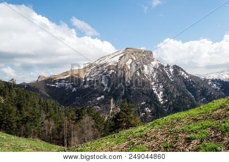 Snow-capped Mountain Top In The Clouds On A Sunny Spring Morning