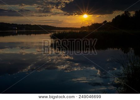 Sunset With Sun Rays At The River Bank. Great Reflection In Water With Reed Plant