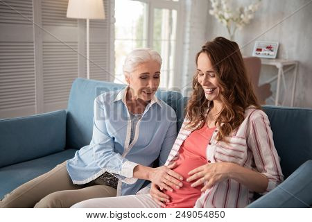 Excited Mother. Beautiful Mature Mother Feeling Extremely Excited While Touching Tummy Of Pregnant D