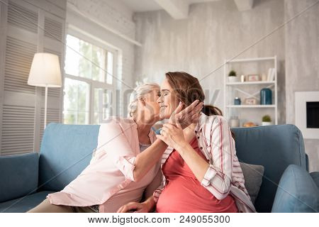 Anticipating Daughter. Caring Loving Mother Feeling Warm And Protected While Kissing Her Anticipatin