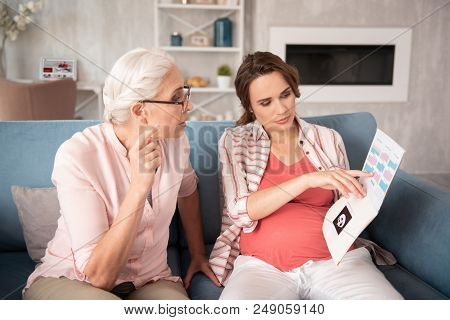 Medical Results. Dark-haired Pregnant Woman Feeling A Little Bit Worried Looking At The Medical Resu