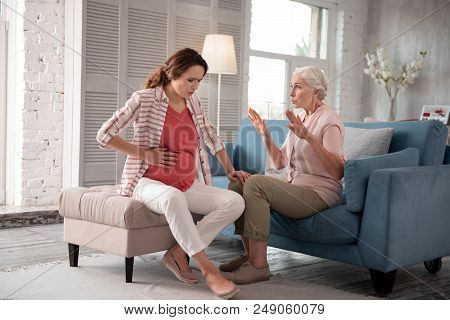 Calming Daughter. Caring Concerned Mother Calming Her Pregnant Daughter Having Severe Ache In Belly