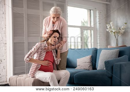 Loving Woman. Loving Appealing Woman Nurturing Her Pregnant Daughter Suffering From Unexpected Pain 