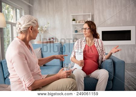 Asking Questions. Modern Pregnant Woman Wearing Black Glasses Asking Private Consultant Curious Ques