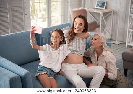Modern Girl. Modern Little Girl Wearing Nice White Blouse Making Selfie With Mother And Grandmother