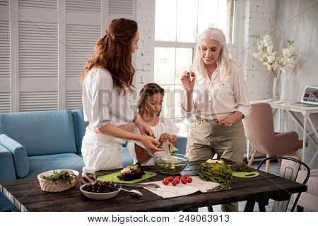 Tomatoes For Salad. Blonde-hared Aged Woman Feeling Busy Cooking Dinner While Holding Cherry Tomatoe