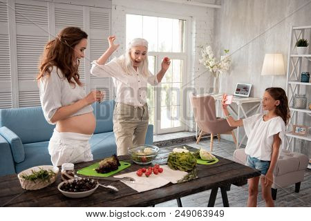 Family Entertainment. Caring Loving Beautiful Grandmother Entertaining Her Family While Cooking Sala
