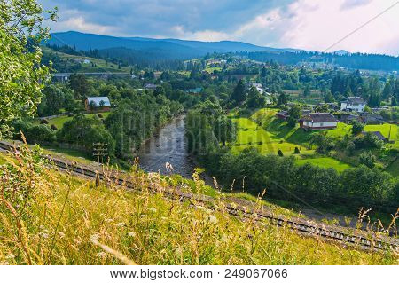 Railway Between The Meadow And The River On The Background Of Village