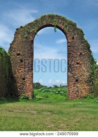 Bricked round arch in a ruin in front of a blue sky.