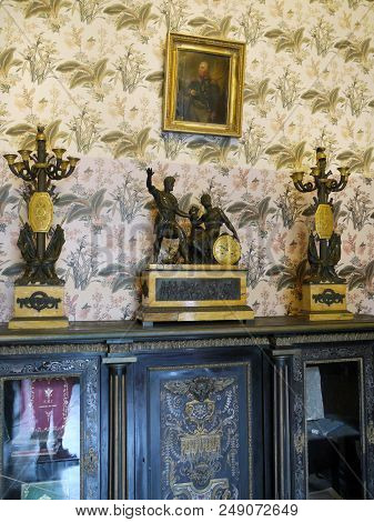 Antique Metal Candlesticks And Decorative Clock On An Antique Chest Of Drawers