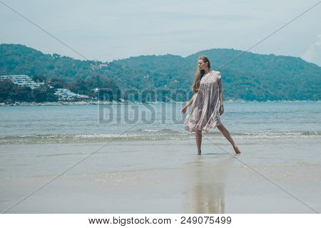 Handsome Girl On The Beach Background. Portrait Of A Woman In White Clothes On The Sea