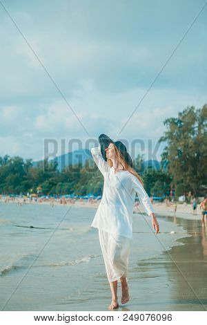 Handsome Girl In Hat On The Beach Background. Portrait Of A Woman In White Clothes And Balck Hat On 