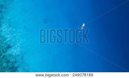 Aerial view of young man riding paddleboard. Paddleboarding is the modern way of transportation and water activity sport.