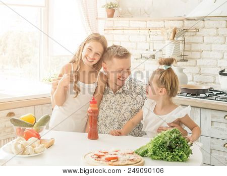dad with two little daughters have a fun in the kitchen