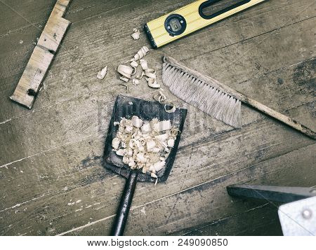 Overhead Filterd Shot Of A Metal Dustpan With Wood Chip On The Wooden Floor
