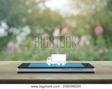 Truck Flat Icon On Modern Smart Phone Screen On Wooden Table Over Blur Pink Flower And Tree, Busines
