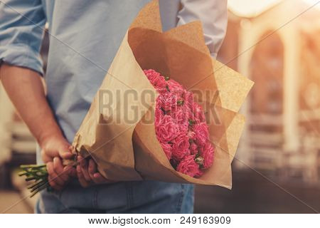Handsome Guy Holding Flowers Behind His Back And Waiting For Beautiful Girlfriend. Magnificent Bouqu