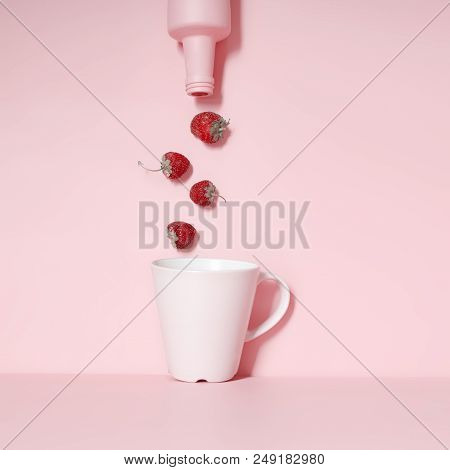 The Strawberry Is Pouring From The Bottle Into The Cup