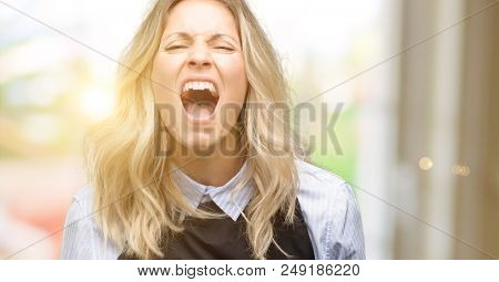 Young shop owner wearing black apron stressful, terrified in panic, shouting exasperated and frustrated. Unpleasant gesture. Annoying work drives me crazy