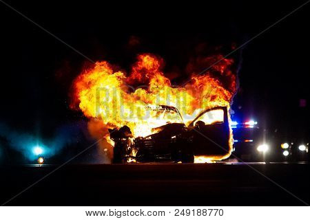 Car On Fire At Night With Police Lights In Background