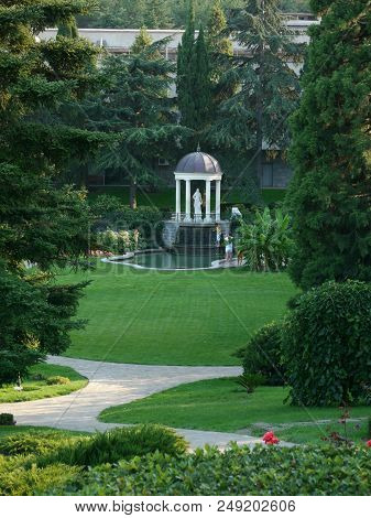 Monument Statue Under The Dome Near The Lake In A Green, Clean Park