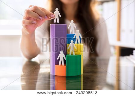 Businesswoman Placing Human Figures On 3D Pie Chart