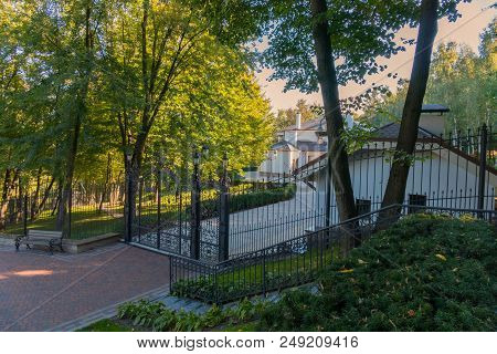 Metal Forged Gate With Lanterns In Front Of The Entrance To The Courtyard Of A Beautiful House