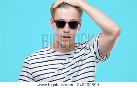 Young handsome blond man wearing sunglasess stressed with hand on head, shocked with shame and surprise face, angry and frustrated. Fear and upset for mistake.