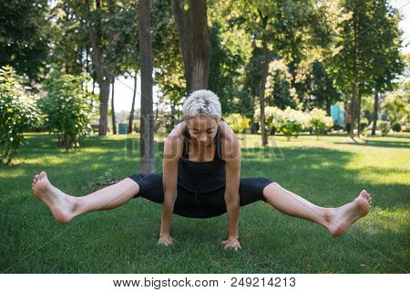 Sportive Woman Practicing Yoga And Doing Positing On Hands In Park