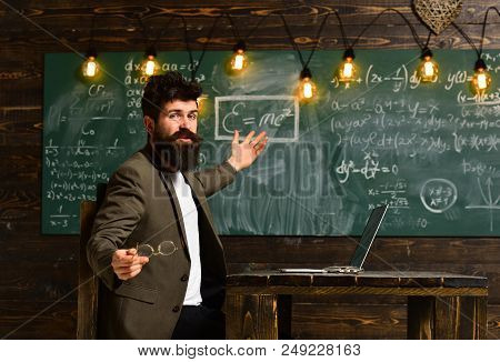 Pretty Teacher Helping Pupil In Classroom At The Elementary School, Tutor Asks The Tutee To Find The