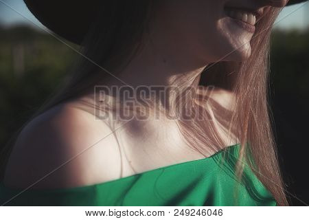 Beautiful Sincere Smile Of A Young Woman. Shadows From The Hat On Her Elegant Collarbone.