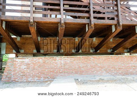 Suspended Solid Wood Deck Structure Detail. Raised Wooden Deck And Hand Guard With Brick Wall Founda