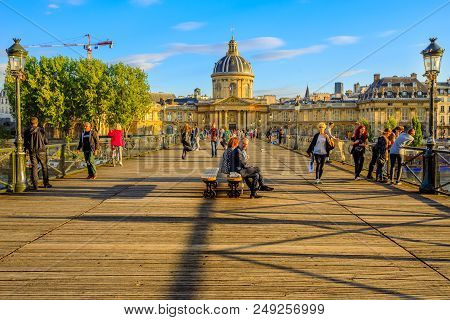 Paris, France - July 1, 2017: Tourists Sitting On Benches Of Pont Des Arts At Sunset, At Pedestrian 