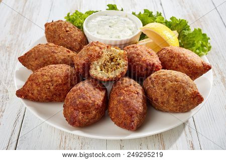 Delicious Kibbeh Stuffed With Fried Beef Ragout And Pine Nuts Served On A White Plate With Lettuce A