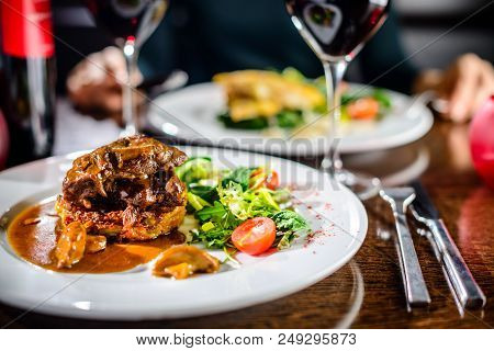 Meat Dish. Appetizing Beef Cheeks In Sauce With Tomatoes And Basil Leaves In A Restaurant, Selective