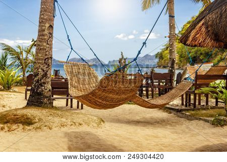 Tropical Beach. A Hammock Between Two Palm Trees On The Beach. Concept Of Rest. Beautiful Beach.