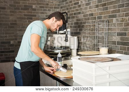 Professional Chef Wearing Black Apron Using Dough Punch Roller Making Fresh Pizza