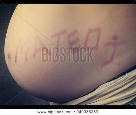Close Up Of A Cute Pregnant Belly With The Name Matthew Written