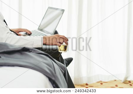 Businesman Drinking Whiskey And Checking E-mails On Laptop
