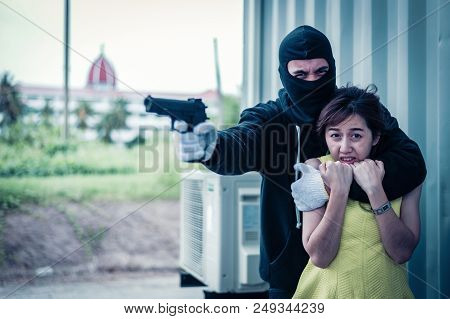 The Villain Locks The Woman's Neck By His Arm For A Hostage And Pointing Gun Forward. He Wear Black 