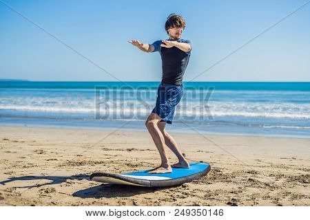 Young Man Surfer Training Before Go To Lineup On A Sand Beach. Learning To Surf. Vacation Concept. S