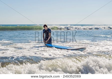 Young Man, Beginner Surfer Learns To Surf On A Sea Foam On The Bali Island.