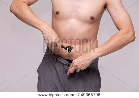 Young Adolescent Muscular Man Trying To Remove His Un-shaved Private Hair Using A Razor