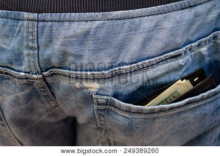 Black Wallet With Money, Sticking Out Of   The Back Pocket Of The Jeans. Nonchalance Concept. Close-