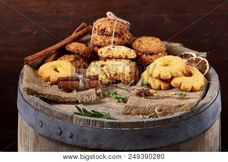 Conceptual Composition With Assortment Of Cookies, Cinnamon Sticks Bunch And Dried Oranges With Burl